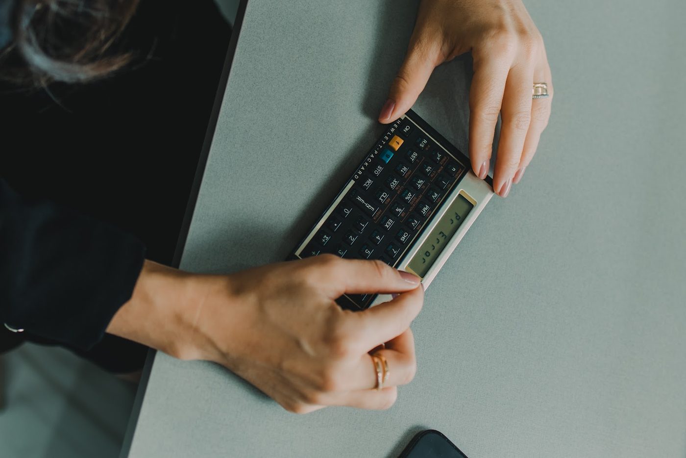 Mãos usando calculadora financeira sobre a mesa